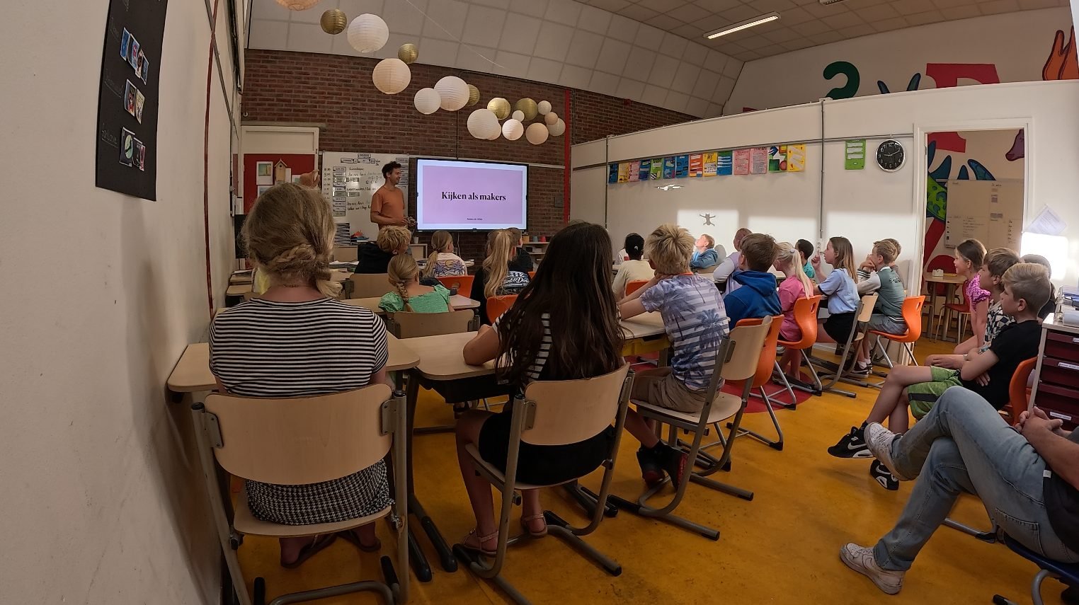 De klas van achteren gezien tijdens een les, met leraren die mee aanschuiven